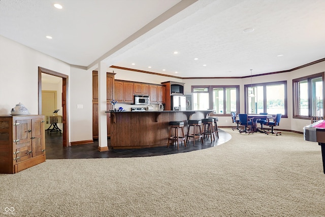 kitchen featuring appliances with stainless steel finishes, kitchen peninsula, ornamental molding, and a breakfast bar area