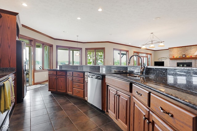 kitchen featuring pendant lighting, sink, a brick fireplace, appliances with stainless steel finishes, and crown molding