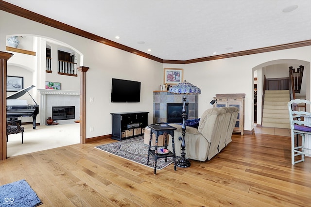 living room featuring light hardwood / wood-style floors, a tile fireplace, and crown molding