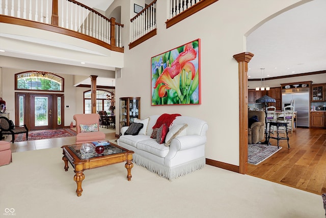 living room with ornate columns, a towering ceiling, dark hardwood / wood-style flooring, and crown molding