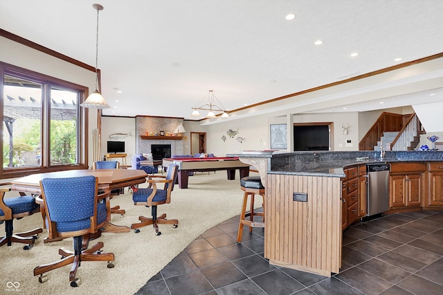 kitchen with dark tile patterned flooring, dishwasher, a breakfast bar area, hanging light fixtures, and a fireplace