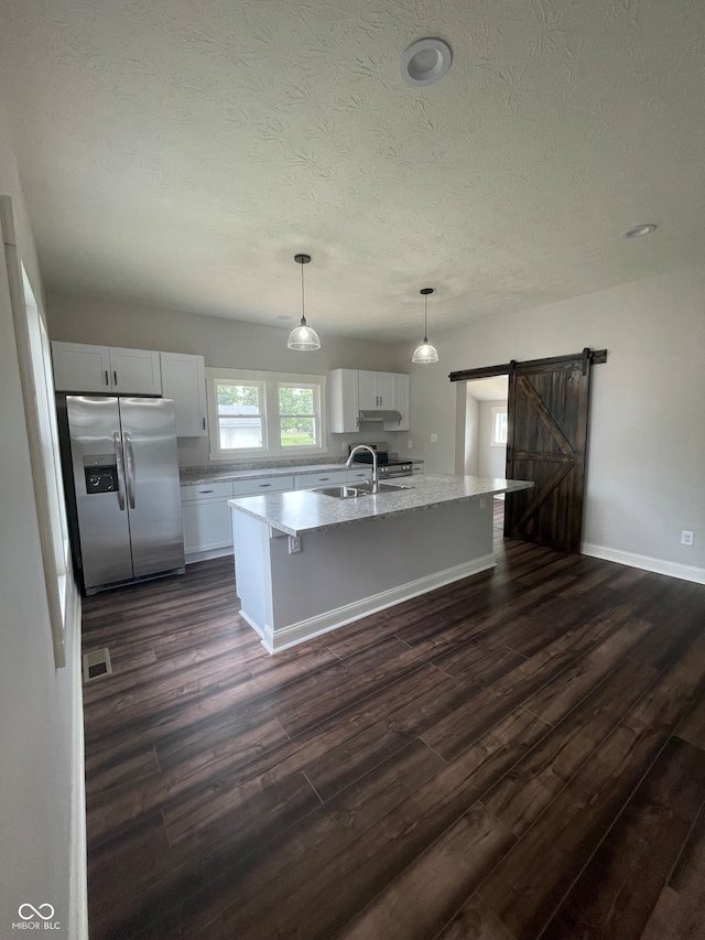 kitchen featuring white cabinetry, a center island, dark wood-type flooring, a barn door, and stainless steel appliances