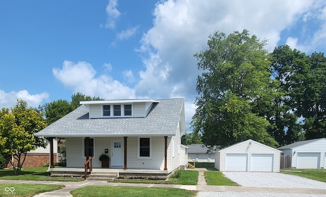 bungalow-style home featuring a porch, a garage, and an outbuilding