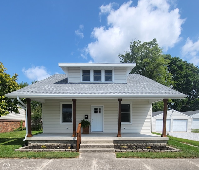 bungalow-style house with a garage, an outbuilding, and covered porch