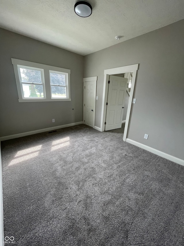 carpeted empty room featuring a textured ceiling