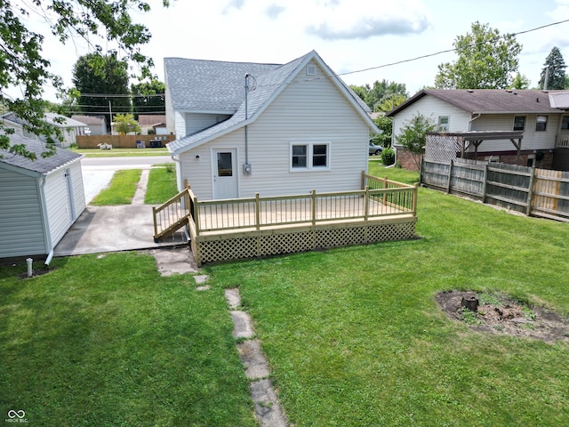 back of house with a wooden deck, a lawn, and an outdoor structure