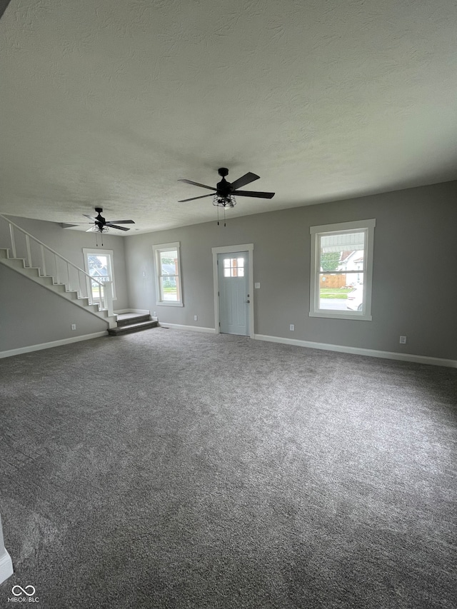 carpeted spare room featuring a textured ceiling and ceiling fan