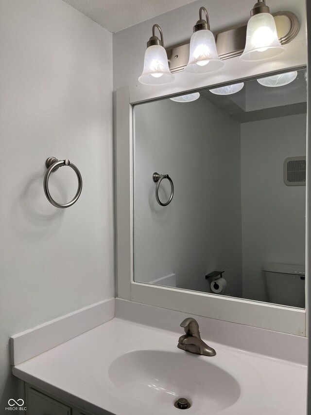 bathroom featuring toilet, vanity, and a textured ceiling