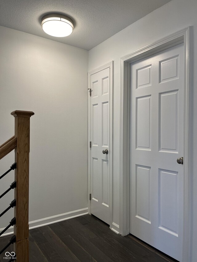 corridor with dark hardwood / wood-style floors and a textured ceiling