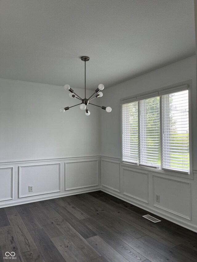 empty room with a chandelier and dark hardwood / wood-style flooring