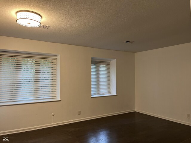 unfurnished room with dark wood-type flooring and a textured ceiling