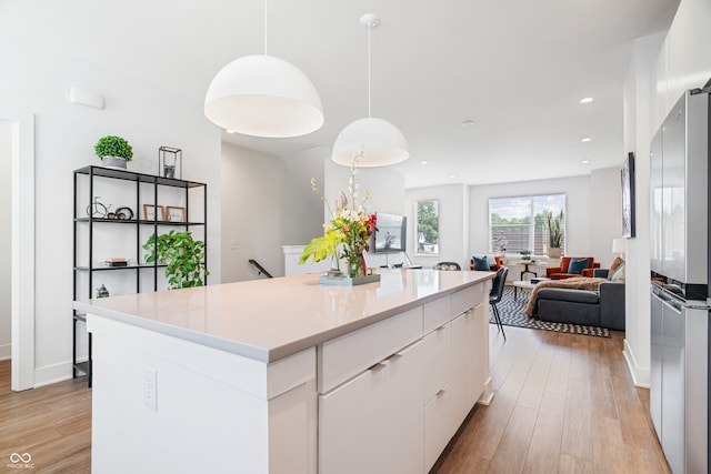 kitchen featuring a kitchen island, white cabinetry, stainless steel fridge, and light hardwood / wood-style floors