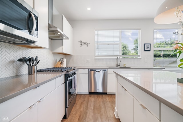 kitchen featuring sink, appliances with stainless steel finishes, decorative backsplash, and wall chimney range hood