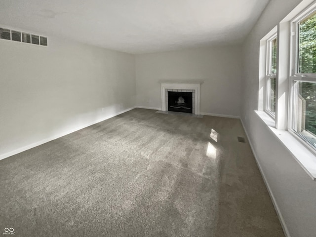 unfurnished living room featuring a tiled fireplace and dark colored carpet