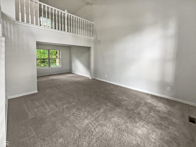 unfurnished living room featuring dark carpet and a towering ceiling