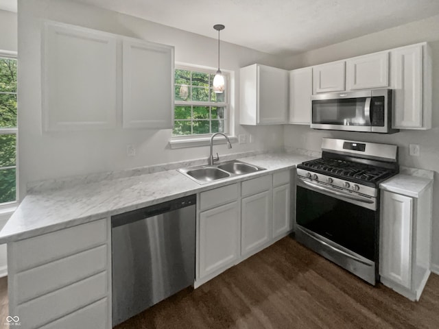 kitchen featuring dark wood-type flooring, sink, pendant lighting, stainless steel appliances, and white cabinets