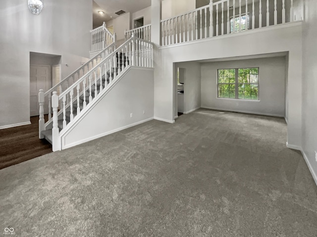 unfurnished living room featuring dark colored carpet and a high ceiling