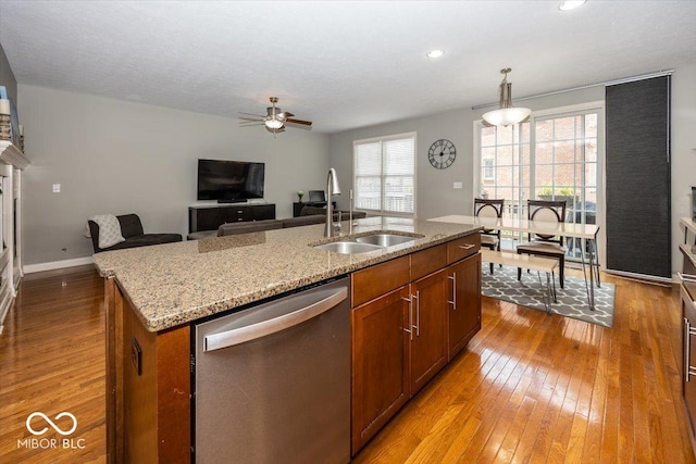 kitchen with an island with sink, a wealth of natural light, stainless steel dishwasher, and light hardwood / wood-style floors