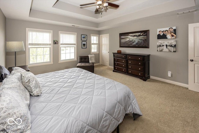 bedroom with light carpet, ceiling fan, and a raised ceiling