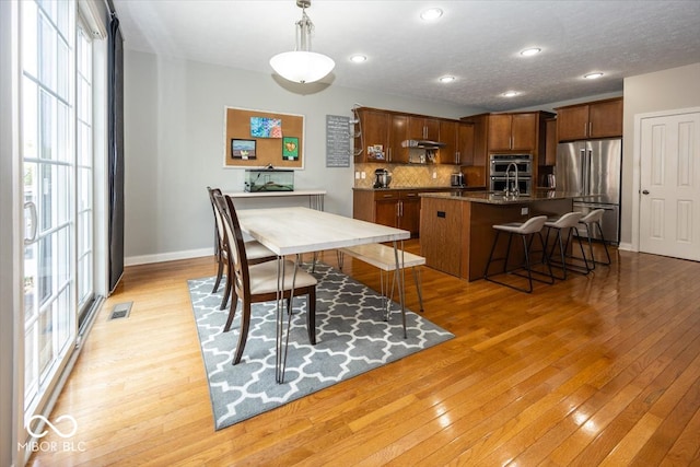 dining space with light wood-type flooring and sink