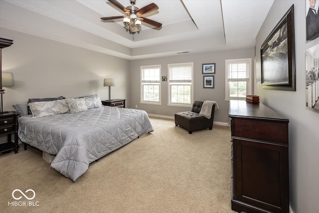 carpeted bedroom with ceiling fan and a raised ceiling