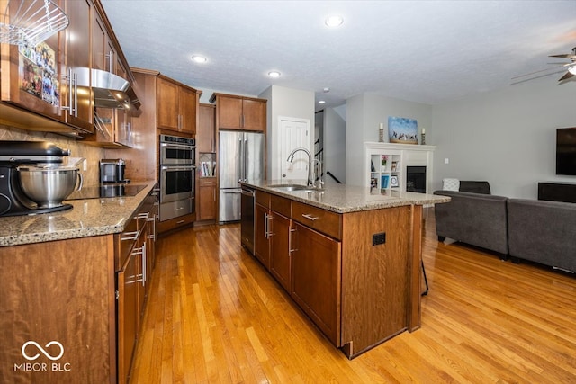 kitchen featuring appliances with stainless steel finishes, light wood-type flooring, sink, and ceiling fan