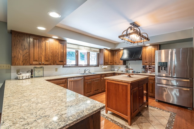 kitchen with light hardwood / wood-style flooring, tasteful backsplash, a kitchen island, stainless steel appliances, and wall chimney exhaust hood