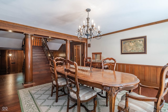 dining space with dark hardwood / wood-style flooring, ornamental molding, an inviting chandelier, decorative columns, and wood walls