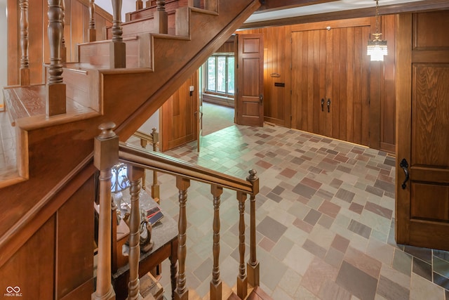stairs with tile patterned floors and wood walls