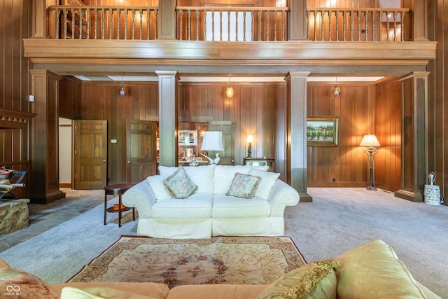 carpeted living area featuring wood walls and ornate columns