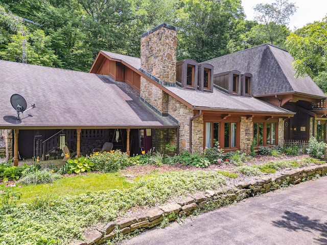 view of front of home with stone siding, a chimney, and roof with shingles