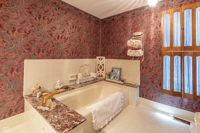 bathroom featuring plenty of natural light, tile patterned floors, tile walls, and a bath