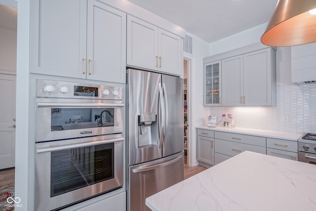 kitchen featuring decorative backsplash, light hardwood / wood-style floors, light stone counters, and appliances with stainless steel finishes