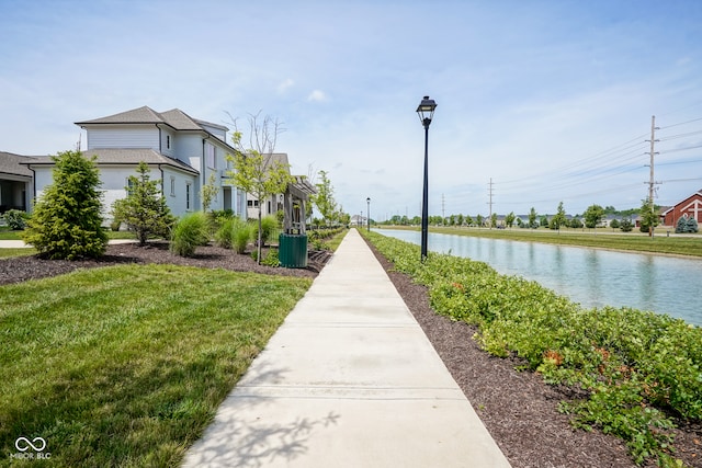 surrounding community with a water view and a lawn