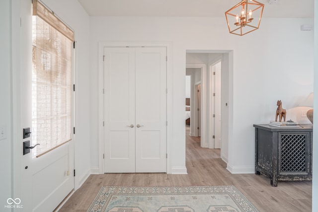 hallway with light hardwood / wood-style floors and a chandelier