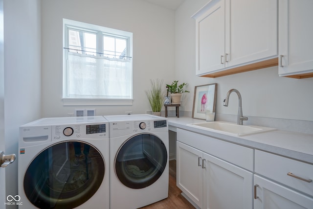 laundry room featuring cabinets, independent washer and dryer, wood-type flooring, and sink