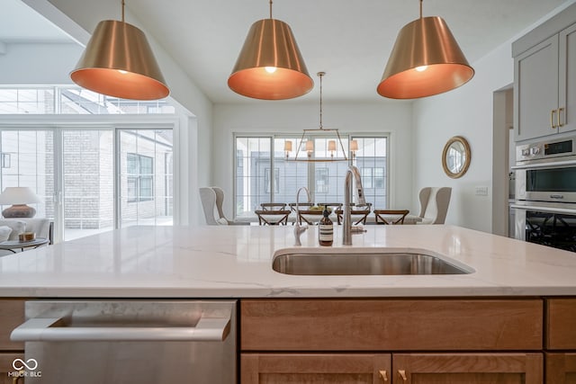 kitchen with light stone counters, gray cabinets, hanging light fixtures, appliances with stainless steel finishes, and sink