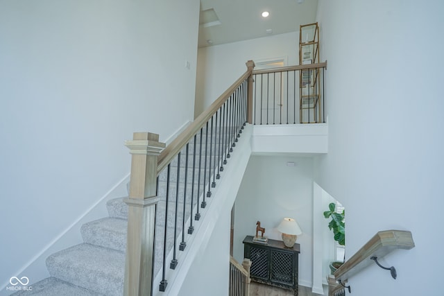 stairs featuring hardwood / wood-style floors and a high ceiling