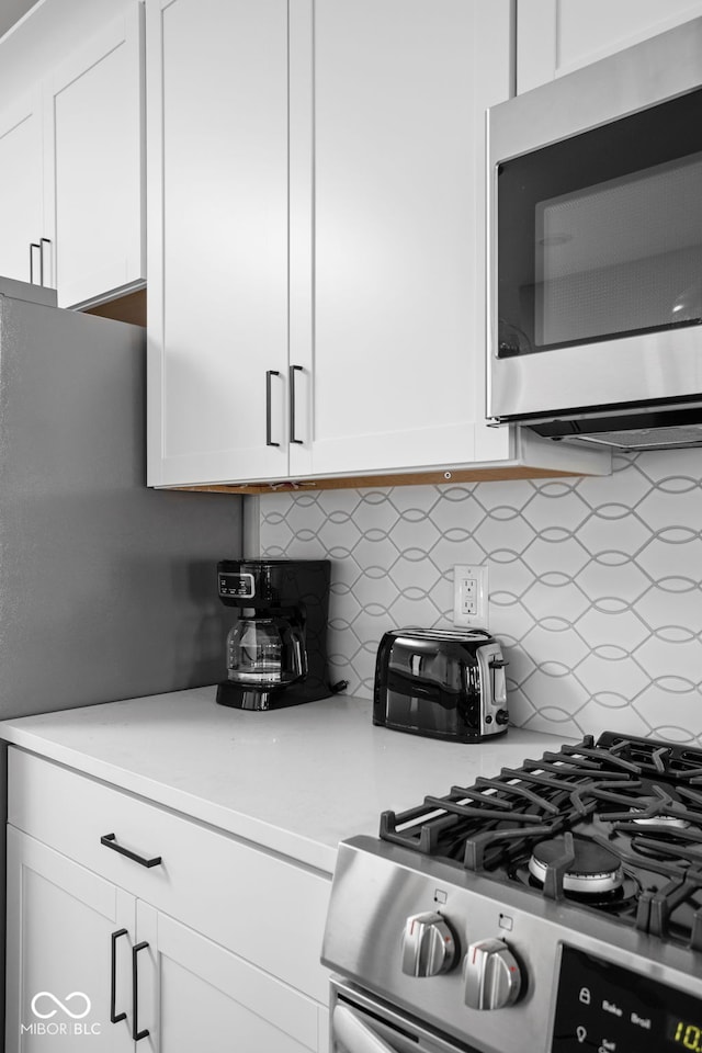 kitchen with white cabinetry, appliances with stainless steel finishes, and backsplash