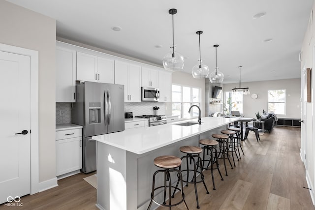 kitchen featuring a large island, sink, stainless steel appliances, and hanging light fixtures