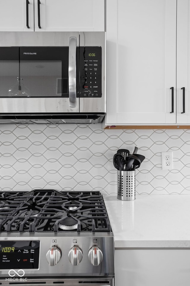 kitchen with stainless steel appliances, white cabinetry, and backsplash