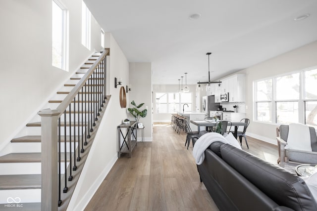 living room featuring a healthy amount of sunlight, sink, and light hardwood / wood-style flooring