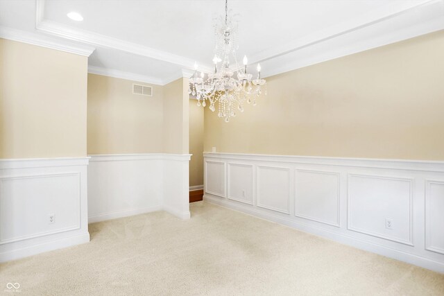 unfurnished dining area featuring visible vents, a chandelier, ornamental molding, carpet floors, and wainscoting