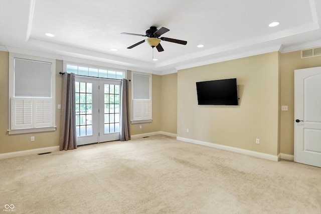 empty room with a ceiling fan, a tray ceiling, carpet, and visible vents