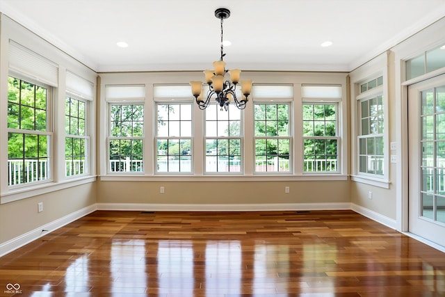unfurnished sunroom with baseboards, wood finished floors, a chandelier, and recessed lighting