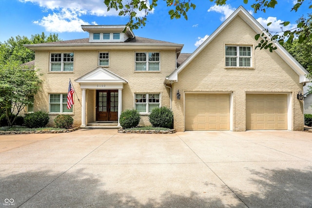view of front of house with brick siding, a garage, french doors, and concrete driveway