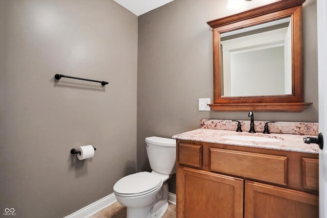 half bath featuring toilet, vanity, tile patterned floors, and baseboards