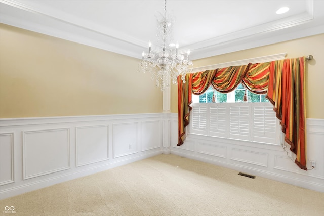 empty room with a raised ceiling, carpet flooring, ornamental molding, and an inviting chandelier