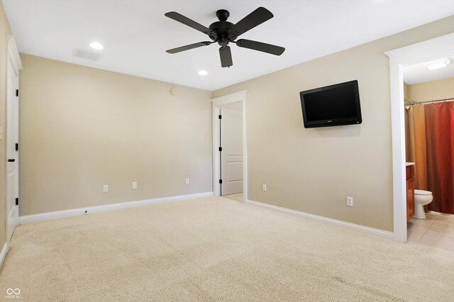 unfurnished bedroom featuring ensuite bath, light carpet, and ceiling fan