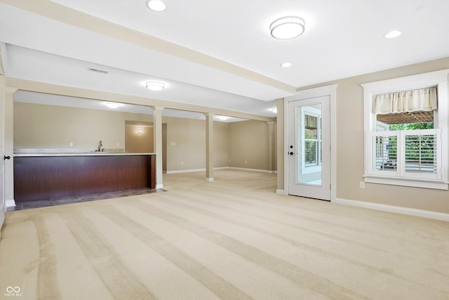 interior space with light colored carpet, recessed lighting, wet bar, baseboards, and a sink